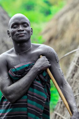 Omo Nehri Vadisi, Etiyopya - 29 Kasım 2020: Mursi kabile köyünde geleneksel giysili Mutlu ve Tatmin Edilmiş Afrikalı Adam Portresi