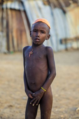 Omo Nehri Vadisi, Etiyopya - 29 Kasım 2020: Sadece yerel Mursi kabilesi köyünde geleneksel ahşap küpeli Afrikalı gençlerin portresi ve kafasında kuru sarı çiçek çelengi)