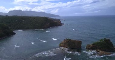 4K Havacılık Manzarası, Dominica Adası 'ndaki Calibishie Sahili' ndeki Okyanus Suyu 'ndaki Rocky Yeşil Dağları gösteriyor.