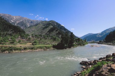 Gilgit Baltistan Highlands, Pakistan 'da Mavi Gök' ün altındaki Fast River ve Green Mountain Ormanı