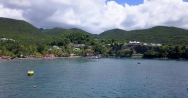 Palmiye ağaçları ve Guadeloupe 'da tatil yapan turistlerle dolu bir sahil.