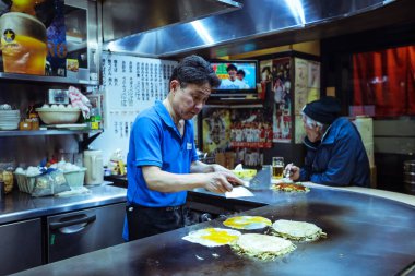 Yerel aşçı Japonya 'daki Hiroşima Restoranı' nda tipik Japon Dişi Okonomiyaki 'yi hazırlıyor.