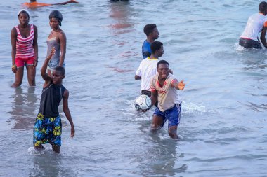Cape Coast, Ghana - April 05, 2022: Local Ghana African People Swimming and having Fun in the warm Atlantic Ocean water