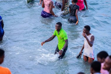 Cape Coast, Gana - 5 Nisan 2022: Yerel Gana Afrikalıları yüzüyor ve sıcak Atlantik Okyanusu 'nda eğleniyorlar