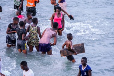 Cape Coast, Ghana - April 05, 2022: Local Ghana African People Swimming and having Fun in the warm Atlantic Ocean water