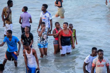 Cape Coast, Ghana - April 05, 2022: Local Ghana African People Swimming and having Fun in the warm Atlantic Ocean water