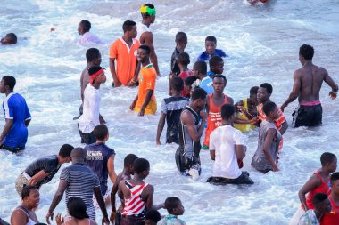 Cape Coast, Gana - 5 Nisan 2022: Yerel Gana Afrikalıları yüzüyor ve sıcak Atlantik Okyanusu 'nda eğleniyorlar