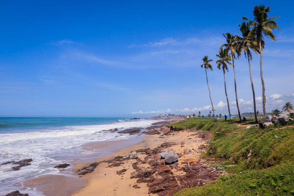 Atlantic Ocean coastline with the turquoise waves among the Palm Trees in Elmina city in Ghana, West Africa