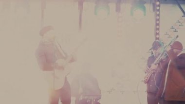 Rock müzisyenleri bir şehir konserinde sahnede çalarlar.