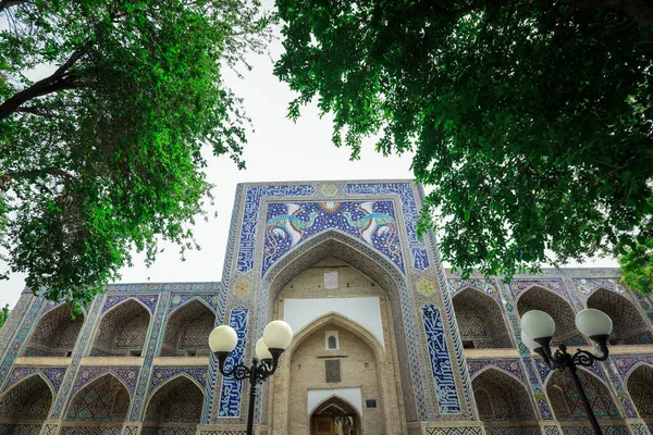 乌兹别克斯坦布哈拉市中心城市广场附近Lab Hauz建筑群的Nadir Divan Beghi Madrasa通过树看到的风景 — 图库照片