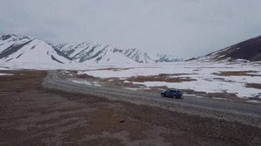 The Road Among Snowy Mountains And A Passing Car, Aerial View