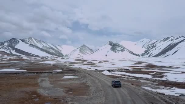 雪山の間の道路と通過車 空中ビュー — ストック動画