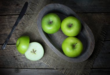 Ahşap bir masada yeşil elmalarla dolu bir hayat.