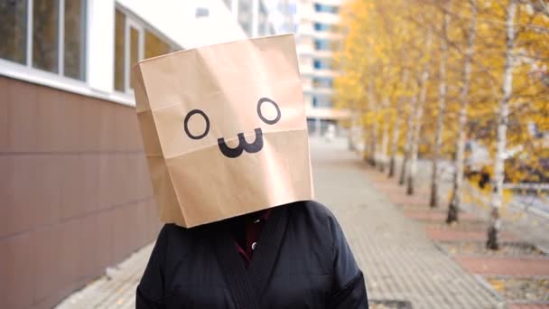 Cara de bolsa de papel divertida caminando por la calle. Retrato de mujer en bolsa de pan sobre la que se dibuja el gato — Vídeo de stock