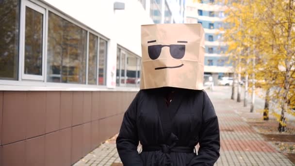 Cool cara saco de papel brilhante andando ao longo da rua. Mulher confiante vestindo saco de pão com óculos de sol — Vídeo de Stock