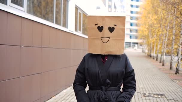 Cara de saco de papel sorridente com olhos de coração andando ao longo da rua. — Vídeo de Stock