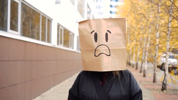 Frightened paper bag face with open mouth walking along street. — Stock Video