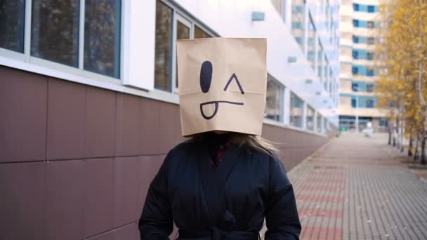 Pazzo fiducioso faccia sacchetto di carta a piedi lungo la strada. Donna divertente che indossa sacchetto di pane con la lingua — Video Stock