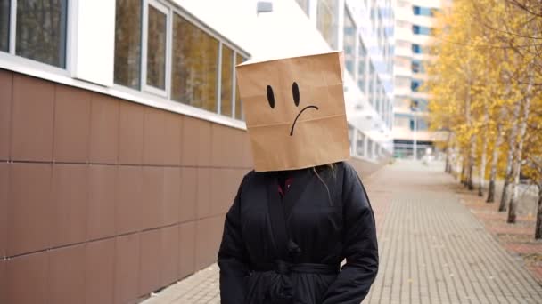 Tråkigt papper väska ansikte med deadpan känslor promenader längs gatan. — Stockvideo