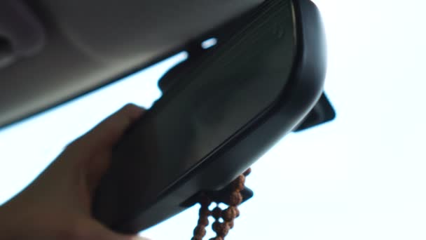 Неузнаваемая женщина регулирует зеркало заднего вида в машине — стоковое видео