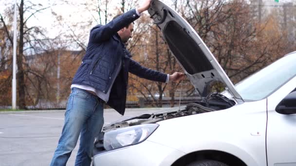Hombre joven abrir la capucha y el control de motor y aceite de coche. Necesidad de reparación. — Vídeo de stock