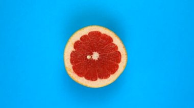 Maviye izole edilmiş sulu bir greyfurdun dönüşü. 360 derece dönüş. Dilimlenmiş kırmızı greyfurt meyvesi.