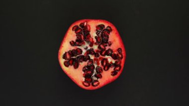 Siyah arka planda dönen bir nar. Taze meyve suyu, sebze, vitamin ve yaz konsepti. Yarım sulu nar manzaralı.