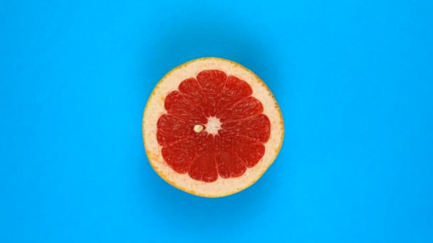 Вращение сочного грейпфрута, изолированного на голубом. Вращение на 360 градусов. Нарезанные красные плоды грейпфрута. — стоковое видео