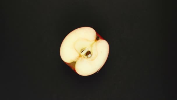 Roterande äpple på svart bakgrund. Färsk juice, frukt, vitamin och sommarkoncept. Ovanifrån av ett halvt saftigt äpple — Stockvideo