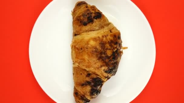 O pão delicioso em uma chapa gira em um fundo vermelho. Croissant fresco — Vídeo de Stock