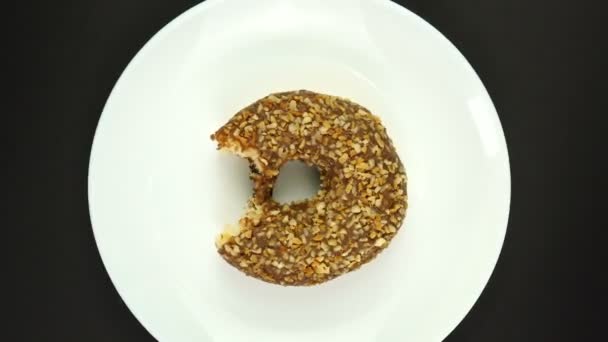 Bitten Donut καλύπτονται σε σοκολάτα Frosting με Sprinkles σε ένα λευκό πιάτο περιστρέφεται — Αρχείο Βίντεο