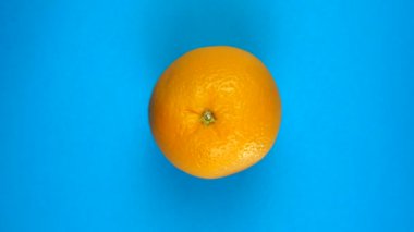 Taze turuncu renkli mavi arka planda dönüyor. Meyve suları, tropik bölgeler ve rahatlama konsepti.