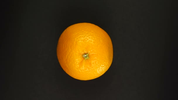 Pomarańczowy obracający się na czarnym tle. Świeże soki, owoce, witaminy i koncepcja lata. — Wideo stockowe