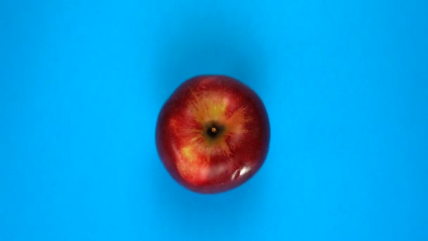 Färskt äpple roterar på en färgad blå bakgrund. Fruktjuice, tropik och avslappningskoncept. — Stockvideo