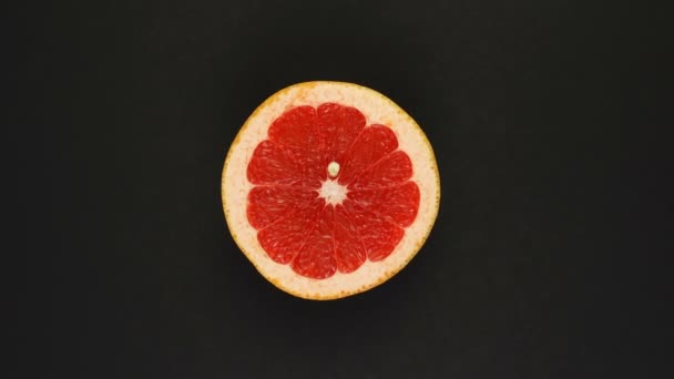 在黑色的背景上旋转柚子.新鲜果汁，水果，维生素和夏天的概念。半个多汁柑橘类的头像 — 图库视频影像