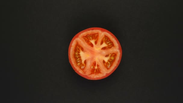 Obracający się pomidor na czarnym tle. Świeże soki, warzywa, witaminy i letnia koncepcja. Widok z góry pół soczystego pomidora — Wideo stockowe