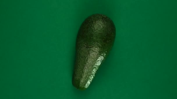 Frutto avocado intero sta ruotando veloce su sfondo verde. — Video Stock