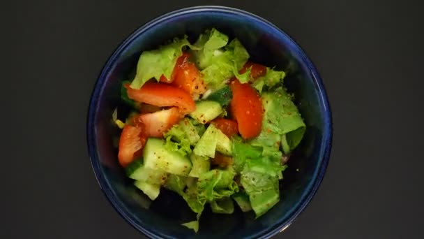 Schüssel Salat dreht sich schnell auf schwarzem Hintergrund. Looping-Aufnahmen — Stockvideo