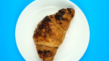 Taze kruvasan mavi arka planda dönüyor. Üst görünüm