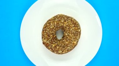 Fırınlanmış çikolatalı çörek tabakta hızla dönüyor. Mavi üzerine izole edilmiş, üst görünüm