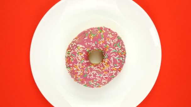 Φρέσκο ψημένο ντόνατ με πολύχρωμο γλάσο περιστρεφόμενο σε κόκκινο φόντο. — Αρχείο Βίντεο