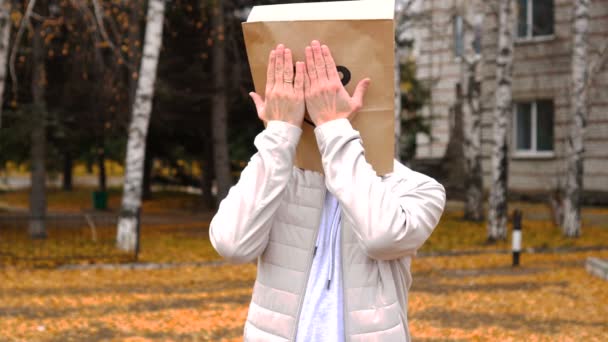 Uomo che indossa sacchetto di carta con emozione felice, uomo in maschera in piedi all'aperto e sopra il suo viso con le sue due mani. — Video Stock