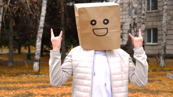 Smiling man wearing paper bag with happy emotion, man in mask standing outdoor and showing gesture of success — Stock Video