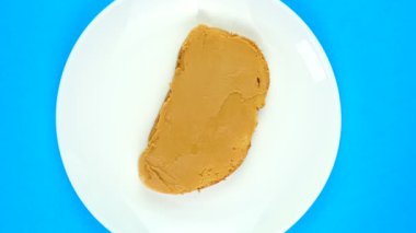 Fıstık ezmeli sandviç tabağı mavi arka planda dönüyor.