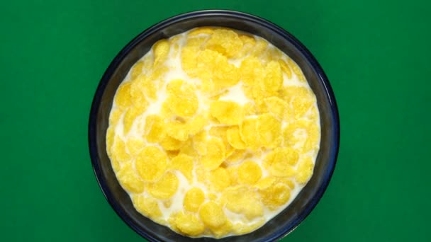 Flocos de milho dourado em leite para café da manhã em fundo verde rotativo, vista superior — Vídeo de Stock