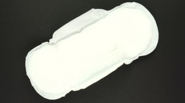 Beyaz adet ve hijyenik peçete siyah arka planda dönüyor. Kadın hijyen ürünleri.