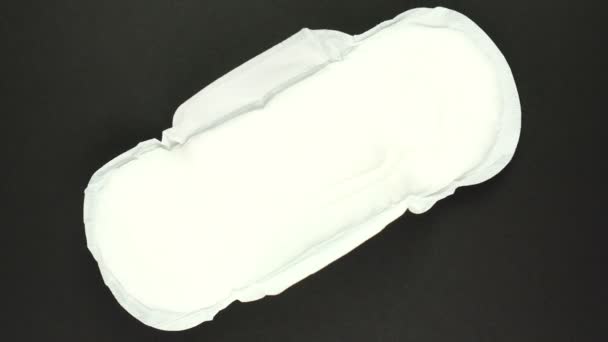 White Menstruation and sanitary napkin pad is rotating on black background. Feminine hygiene product — Stock Video