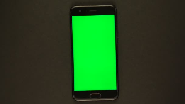 Smartphone with green screen rotates on black background — Stockvideo