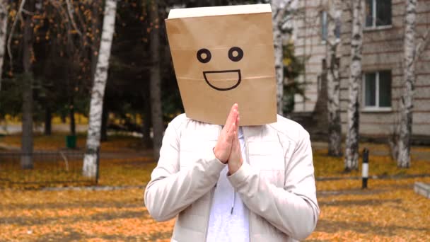 Glimlachende man draagt papieren zak met blije emotie, man met masker buiten staan en wrijven zijn handpalmen — Stockvideo
