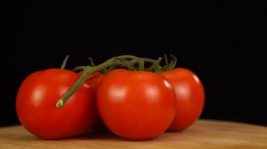 Tahta bir masada olgun taze domatesler var ve dönüyor. Yakın plan taze sebzeler..